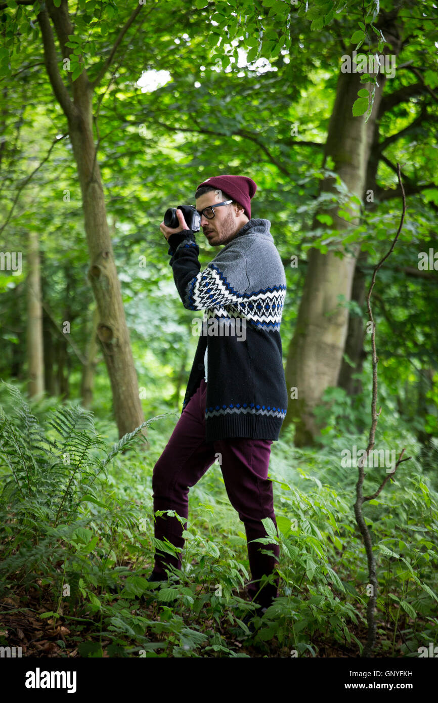 Portrait of man taking landscape photos with a DSLR in a forest. Caucasian Photographer shooting outside with digital camera. Stock Photo