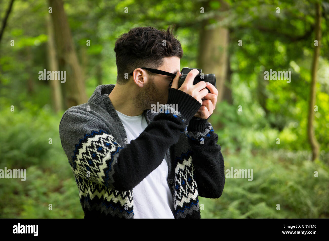 Portrait of man taking landscape photos with a DSLR in a forest. Caucasian Photographer shooting outside with digital camera. Stock Photo