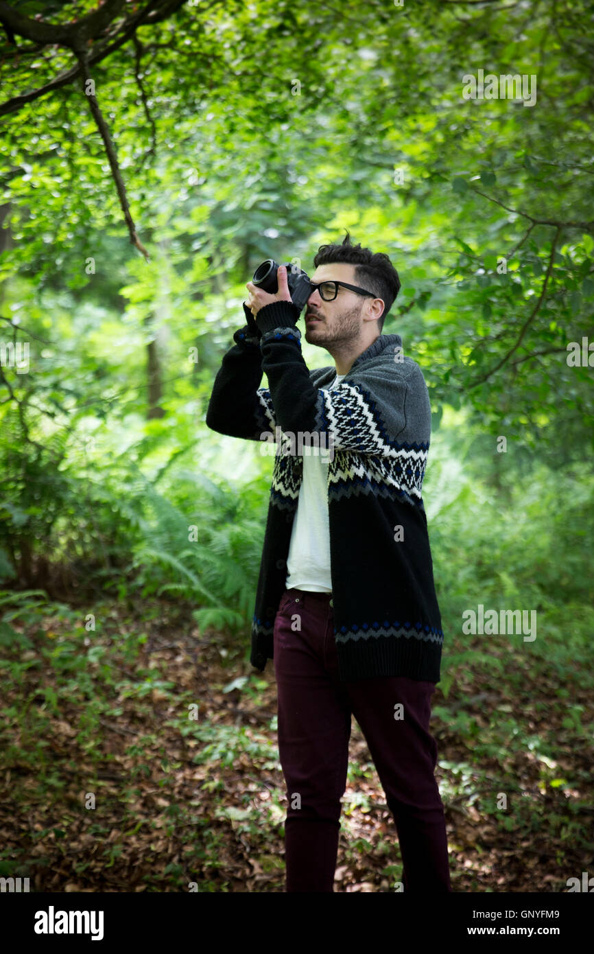 Portrait of man taking landscape photos with a DSLR in a forest. Caucasian Photographer shooting outside with digital camera. Stock Photo