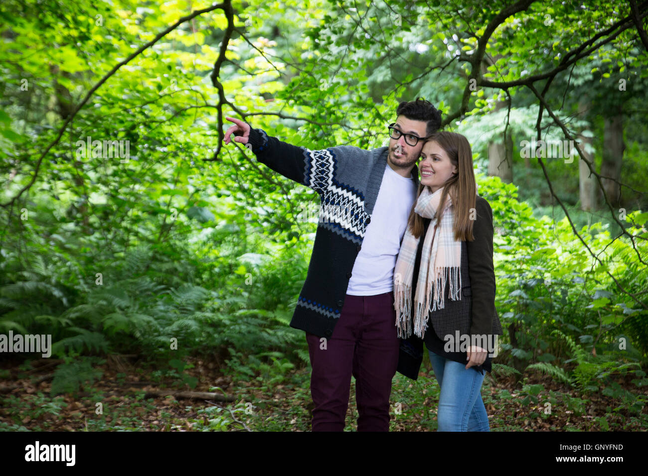 Relaxed young couple holding hands while walking through forest. Caucasian lifestyle concept. Stock Photo