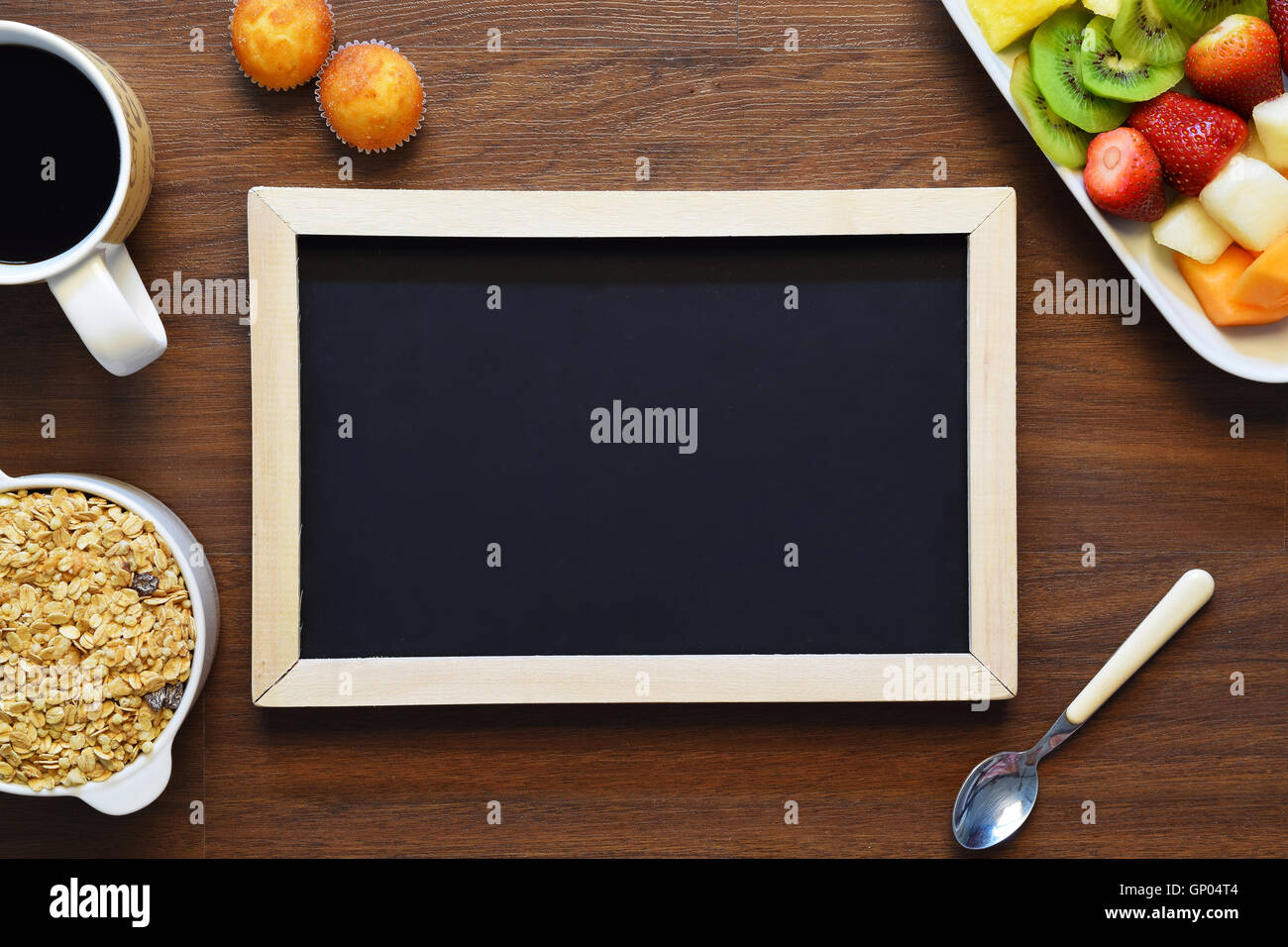 Chalkboard with copyspace surrounded by bowl of granola, fruit platter