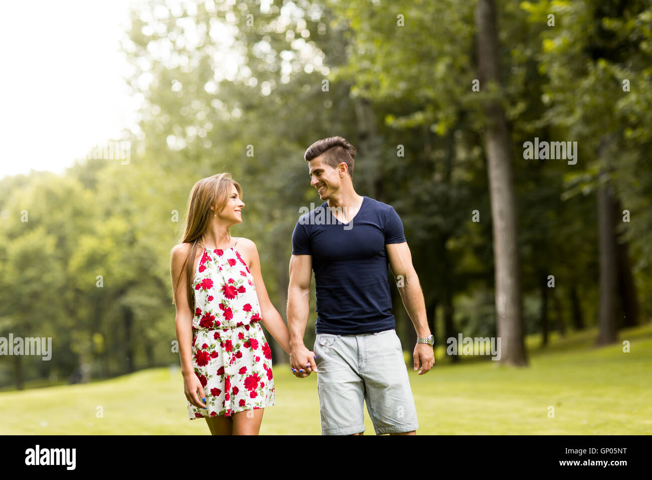 Young couple in love standing in the park and holding hands Stock Photo ...