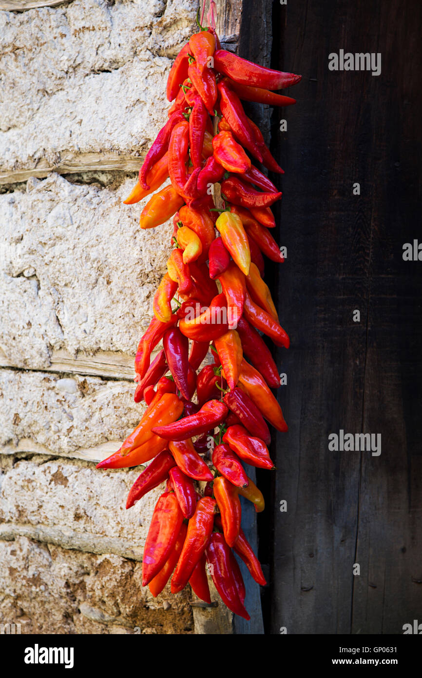 Red Paprika Peppers traditionally hanging To Dry On The Wall Of A House Stock Photo