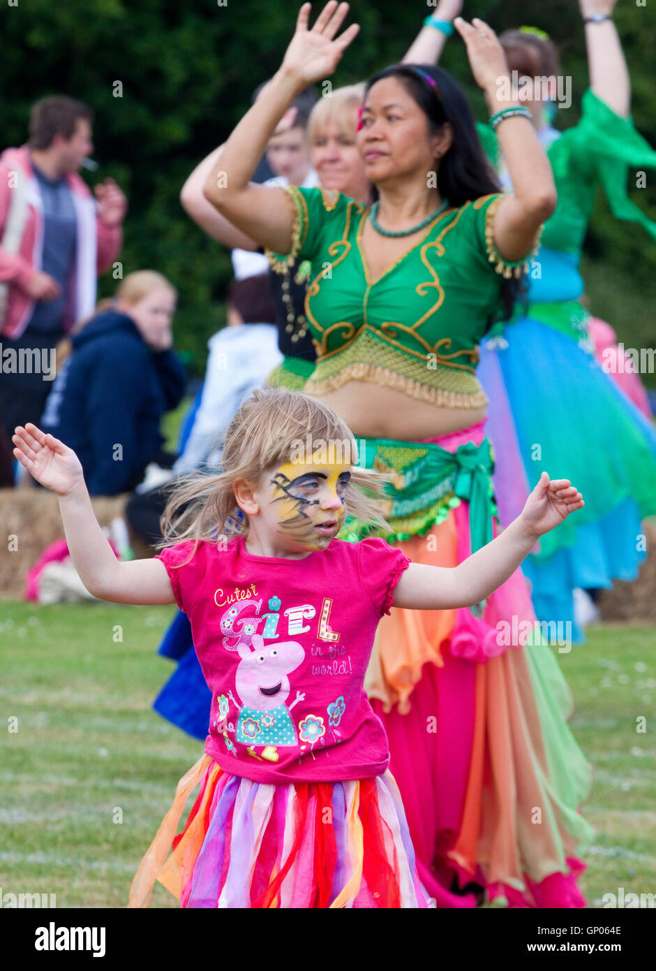 Face painted little girl joins in belly dancers Stock Photo