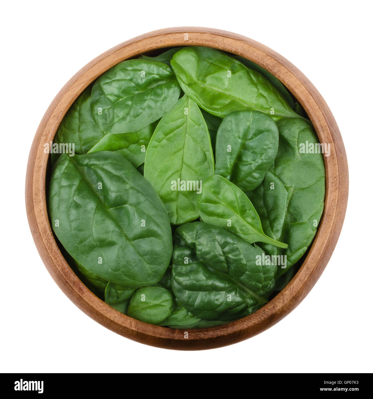 Fresh green spinach leaves in a wooden bowl on white background. Spinacia oleracea, edible flowering plant. Stock Photo