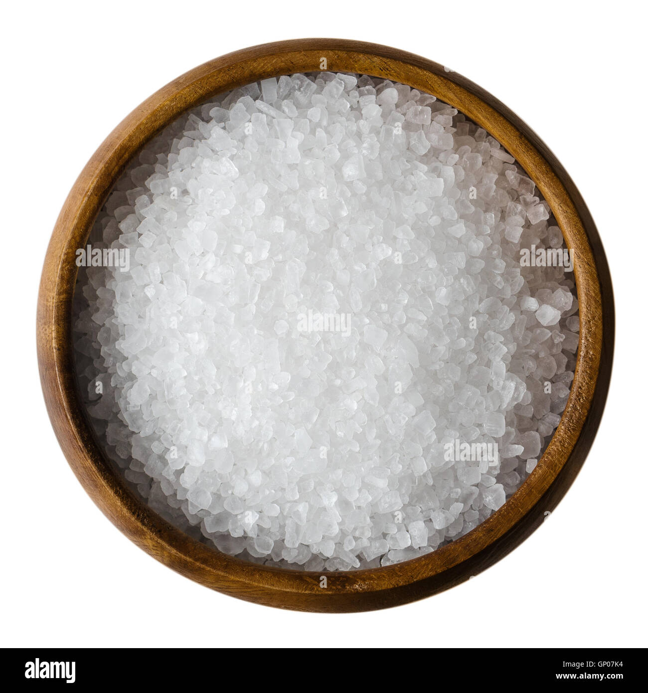 Sea salt in a wooden bowl on white background. Also called bay salt or solar salt, is used in cooking and cosmetics. Stock Photo