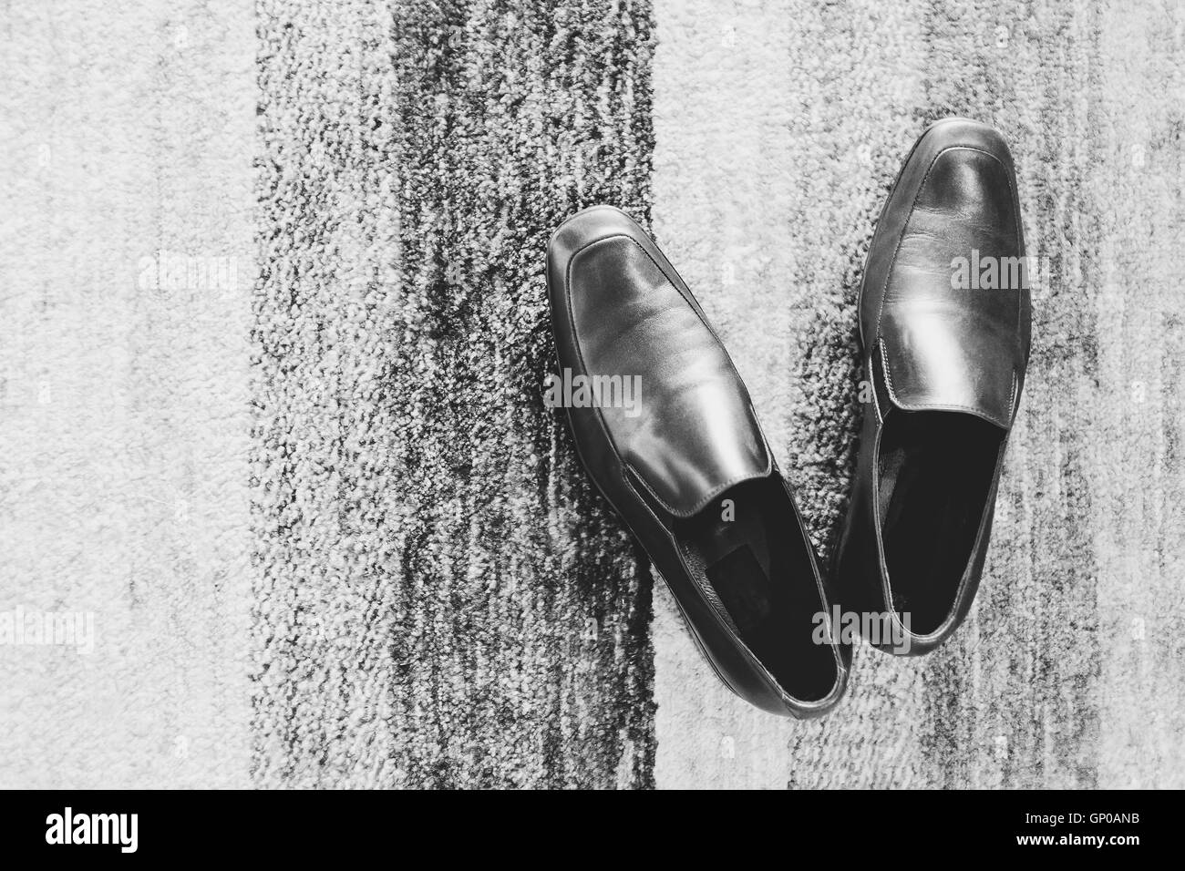 A pair of black leather shoes on carpet. Black and White. Stock Photo