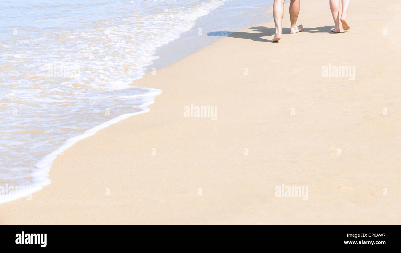 Couples walking on tropical sandy beach in vacations. Shadow on sand. Stock Photo