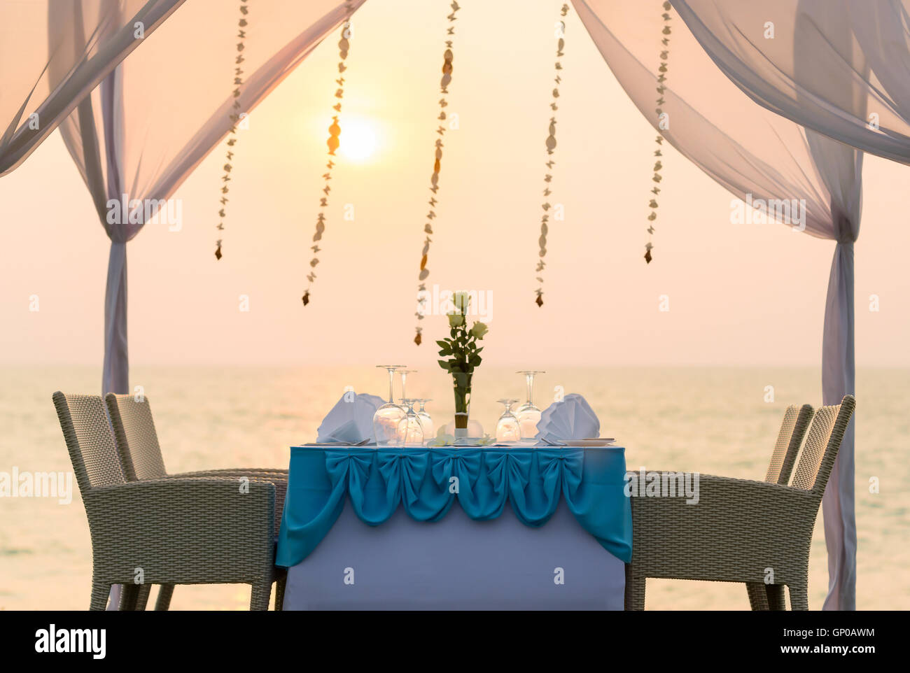 Romantic dinner setting on the beach at sunset. Stock Photo