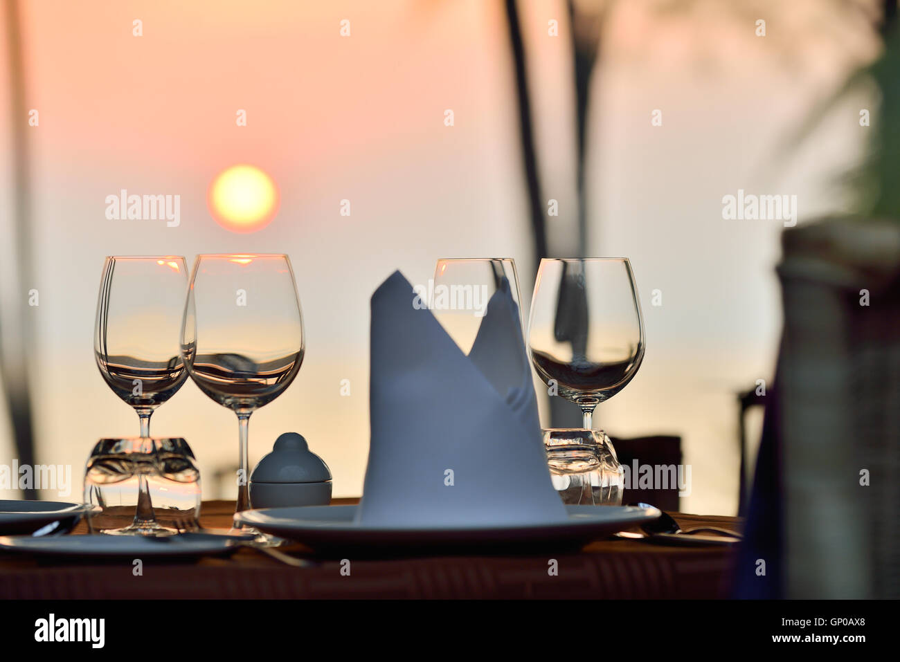 Romantic dinner table setup at a beach side restaurant on sunset. Stock Photo