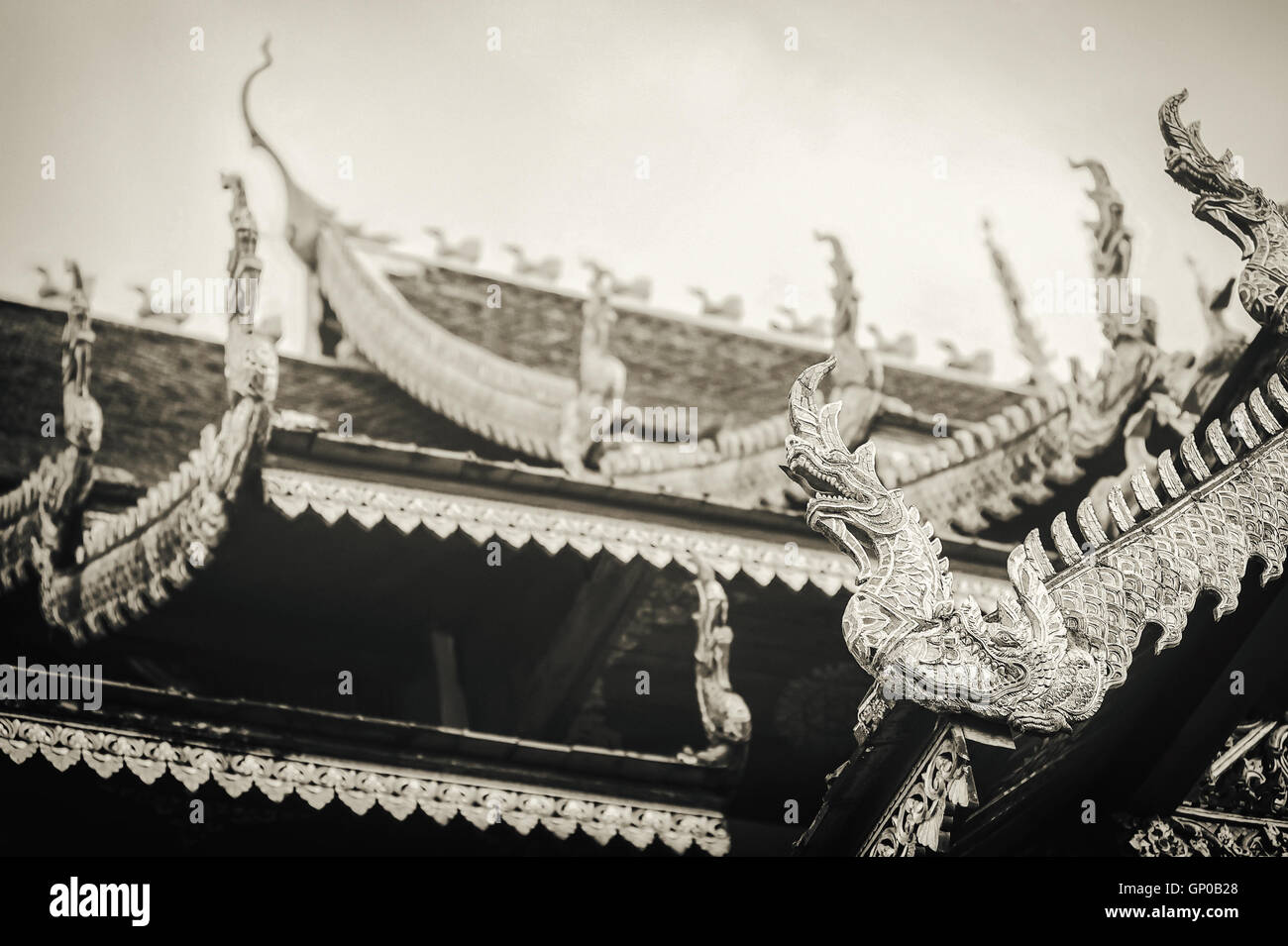 Thailand art and architecture: Naga wood carved on roof at Thai temple. Sepia tone. Stock Photo