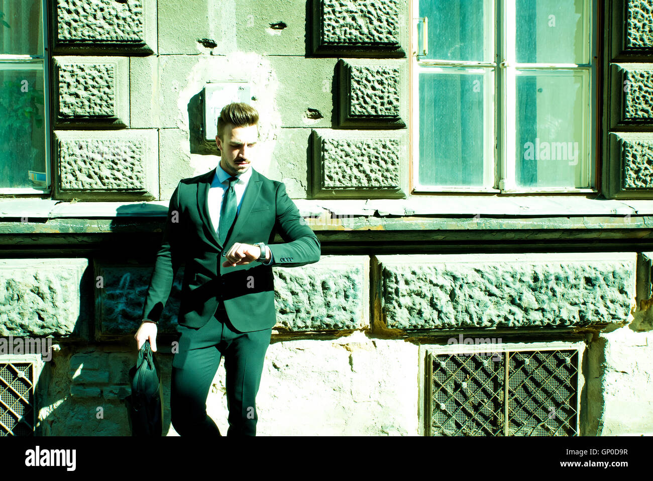 Young businessman waiting outside on the street checking the time on ...