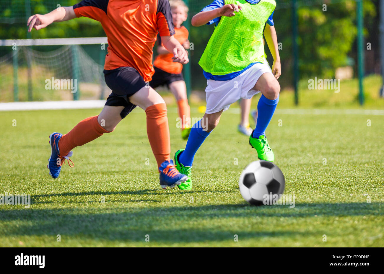 Young boys kicking soccer ball on sports field. Youth football