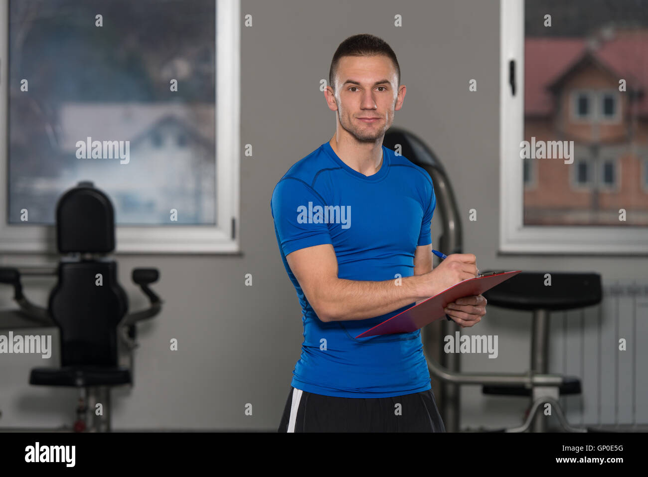 Personal Trainer In Sports Outfit Takes Notes On Clipboard In A Fitness