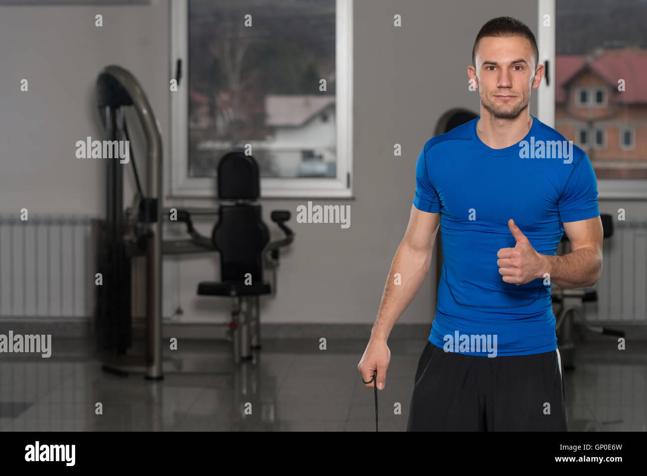 Handsome Personal Trainer With Stopwatch Showing Thumbs Up Sign In A