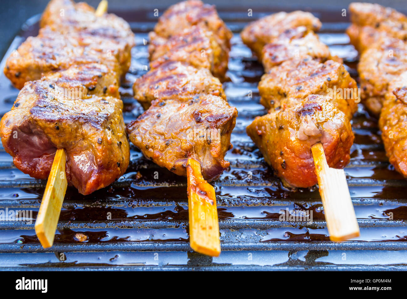 pan fried round steak cubes on sticks in a grill pan Stock Photo Alamy