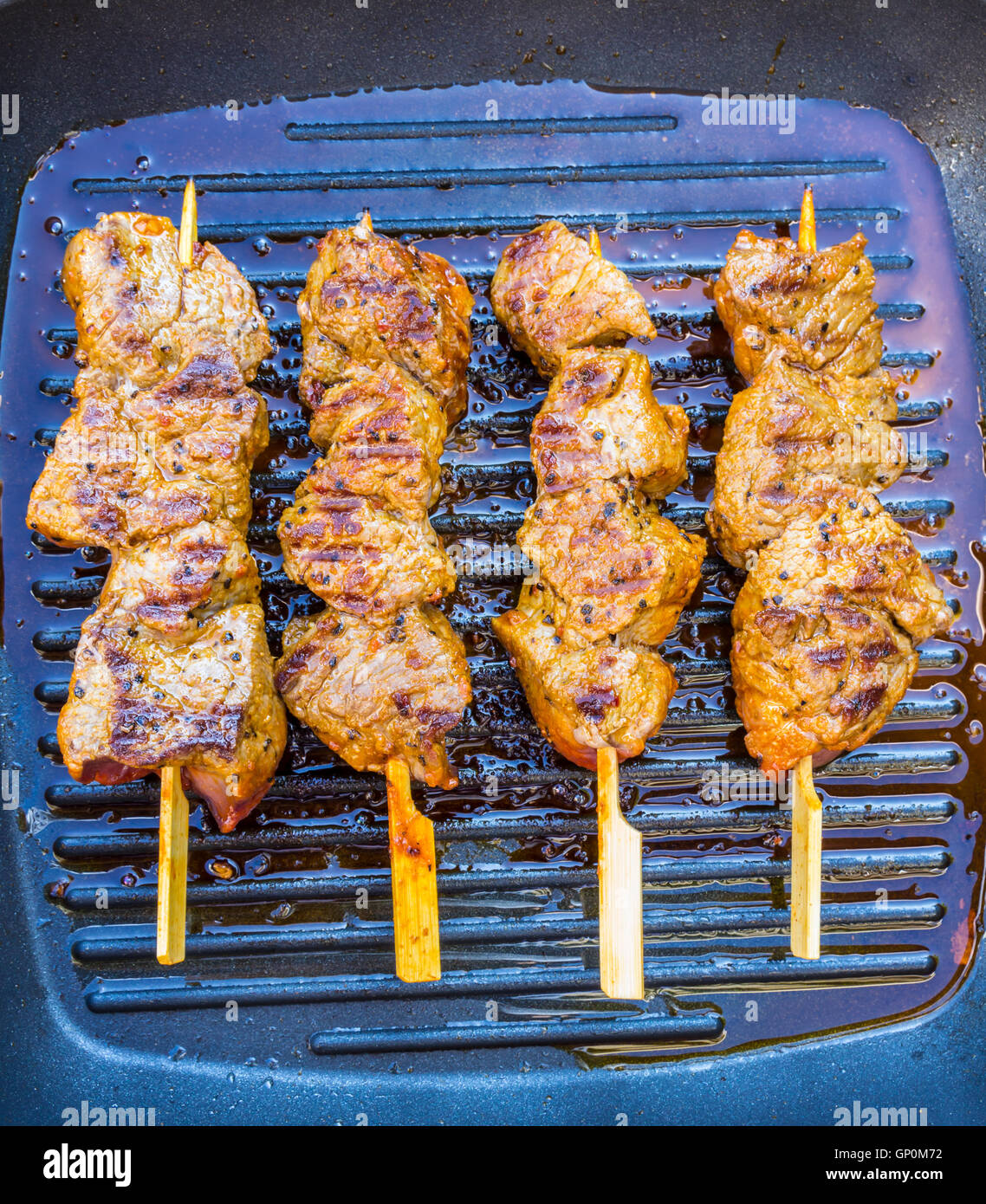 pan fried round steak cubes on sticks in a grill pan Stock Photo Alamy