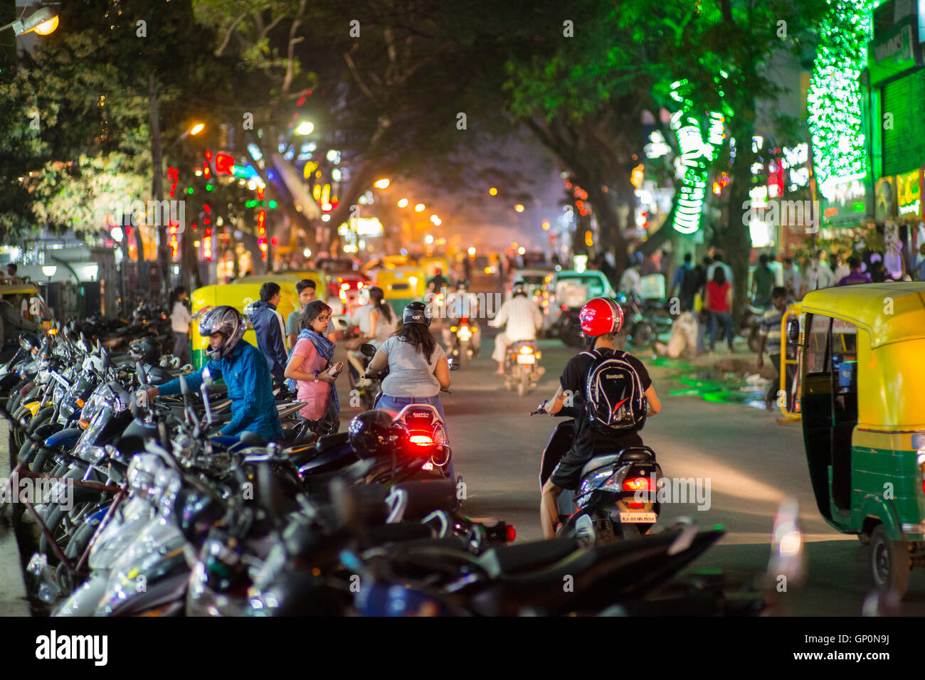 The street is filled with people and scooters in the popular party area at night in Bangalore, India Stock Photo