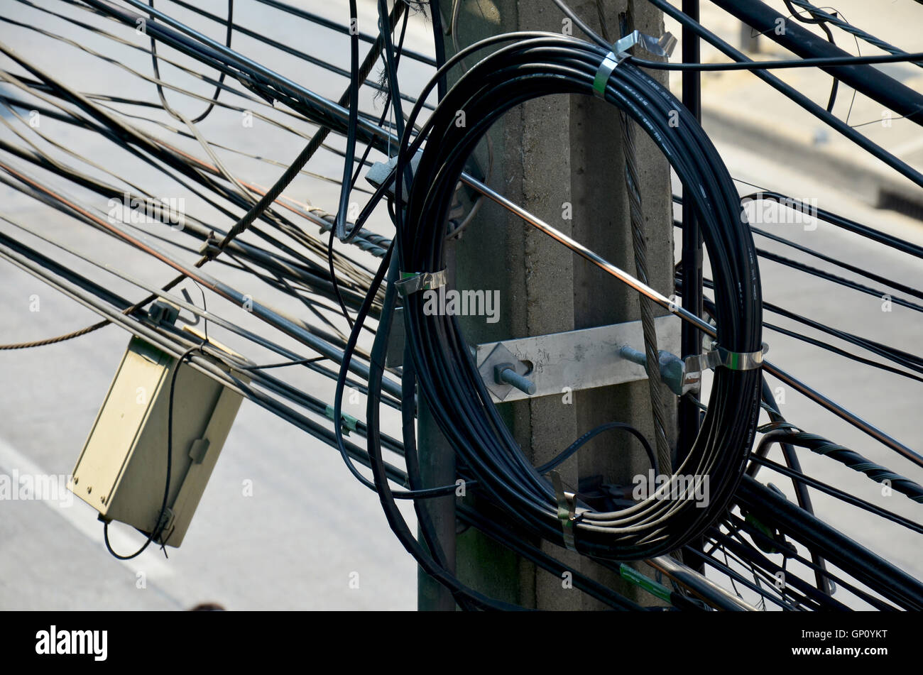 Many wires messy with power line cables, transformers and phone lines on electricity pillar or Utility pole at beside road on Ap Stock Photo