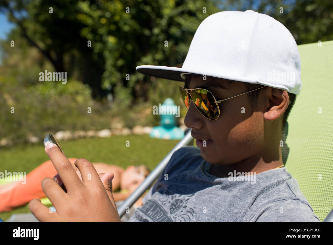 Young boy wearing a white hat watching his smartphone Stock Photo