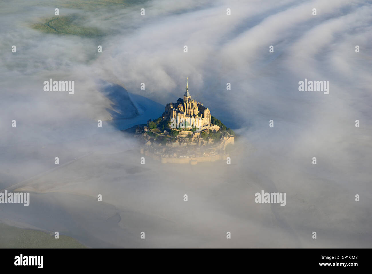 AERIAL VIEW. Abbey on an isolated peak above the morning fog. Mont Saint-Michel, Manche, Normandy, France. Stock Photo