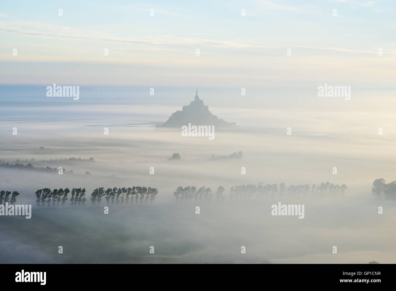 AERIAL VIEW. Mont Saint-Michel silhouetted against the early morning fog. Manche, Normandie, France. Stock Photo