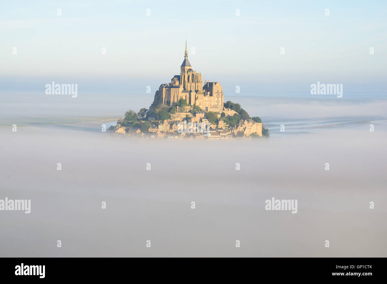 AERIAL VIEW. Abbey on an isolated peak above the morning fog. Mont Saint-Michel, Manche, Normandie, France. Stock Photo