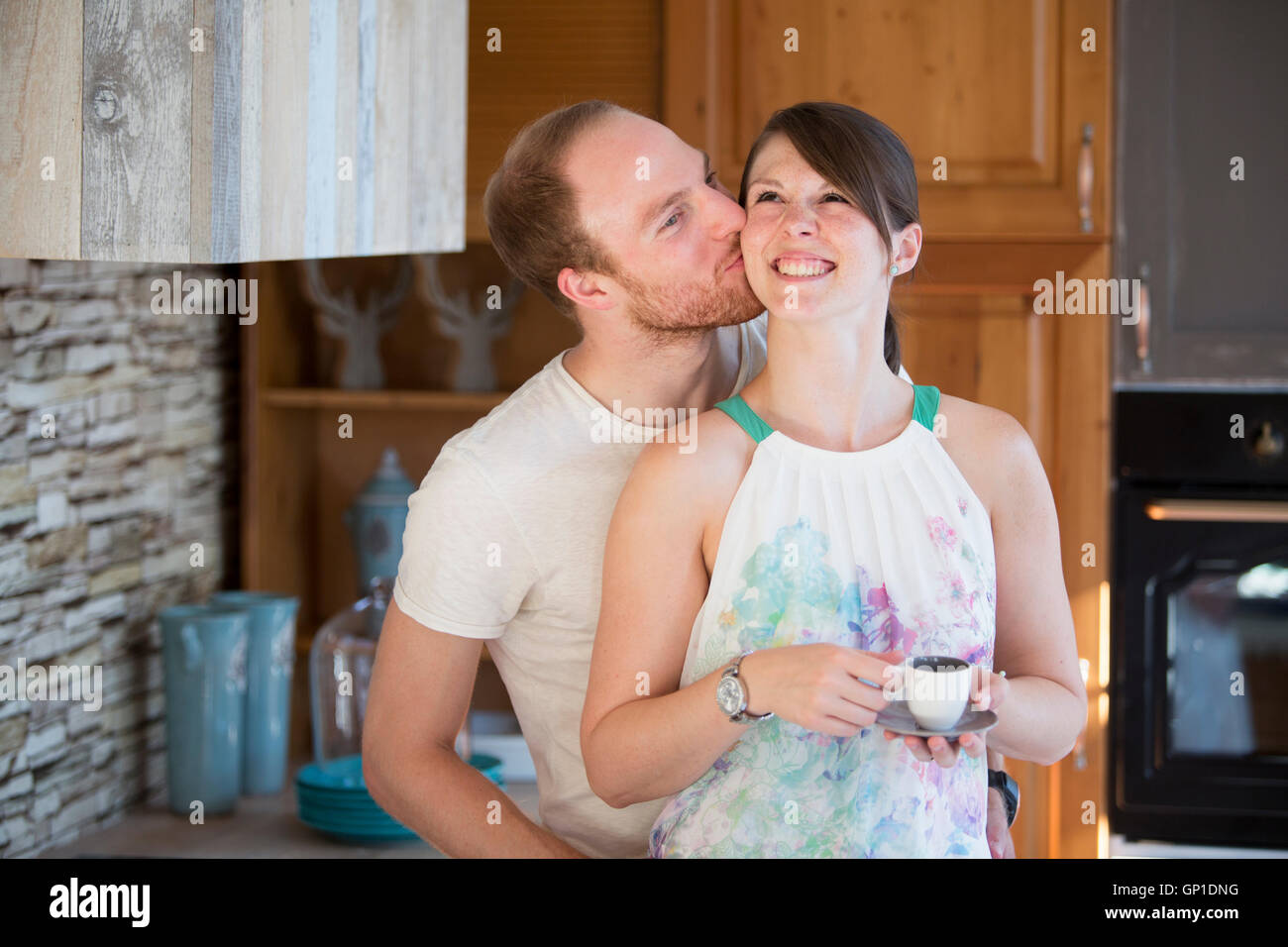 young man kissing his woman in kitchen Stock Photo