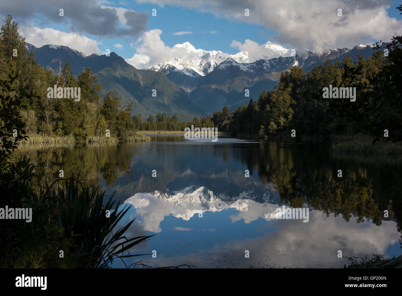 Lake Matheson is reflecting the Southern Alps with its highest peaks Mount Cook (right) and Mount Tasman (left). Stock Photo