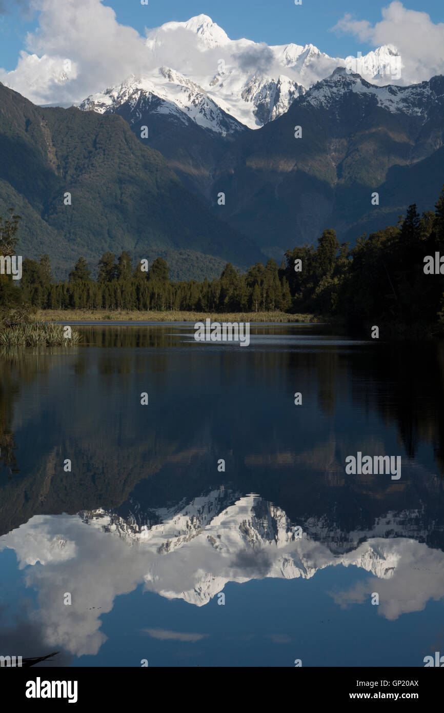 Lake Matheson is reflecting the Southern Alps with its highest peaks Mount Cook (right) and Mount Tasman (left). Stock Photo