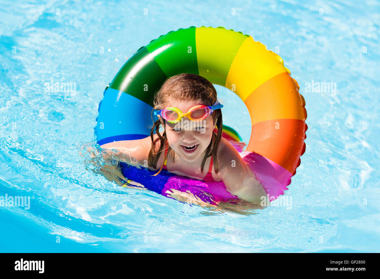 Happy little girl playing with colorful inflatable ring in outdoor ...