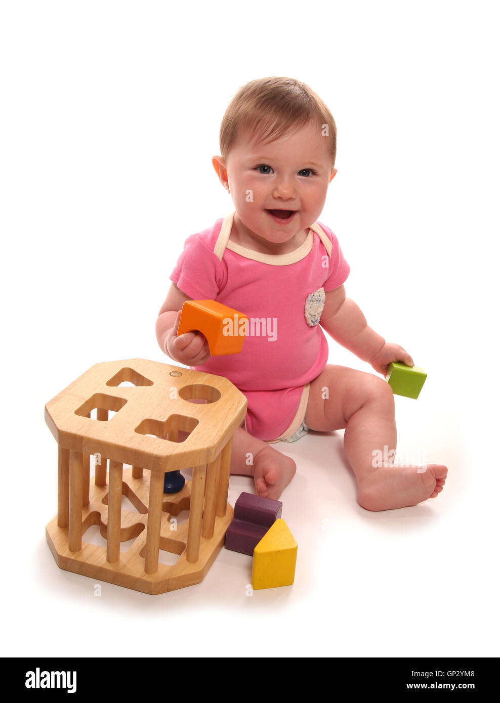 Baby girl playing with wooden shape sorter cutout Stock Photo