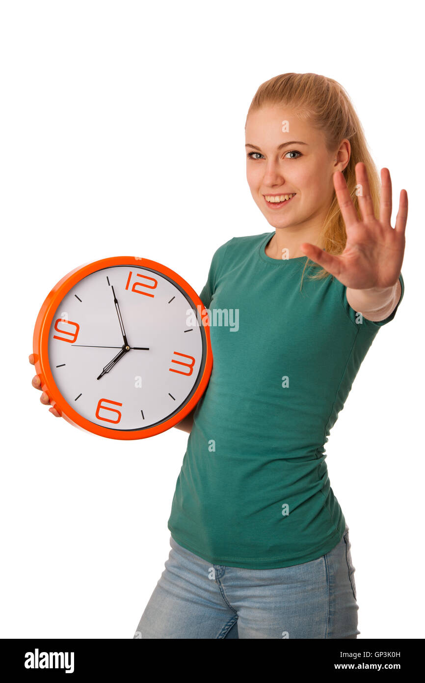 Blonde woman holding big clock in hand, gesturing five minute to seven