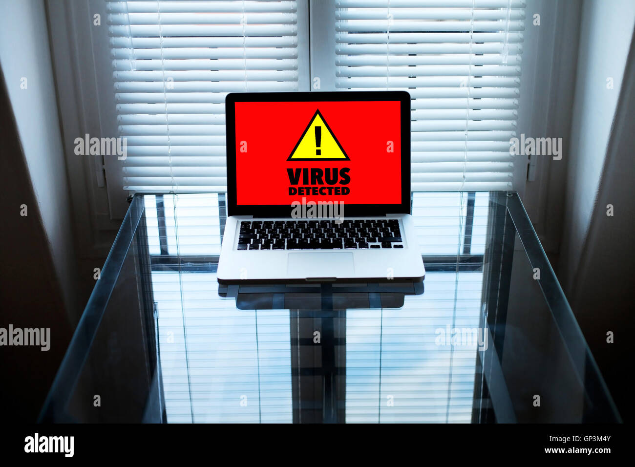 computer virus, alert sign on the screen of laptop in dark room Stock Photo