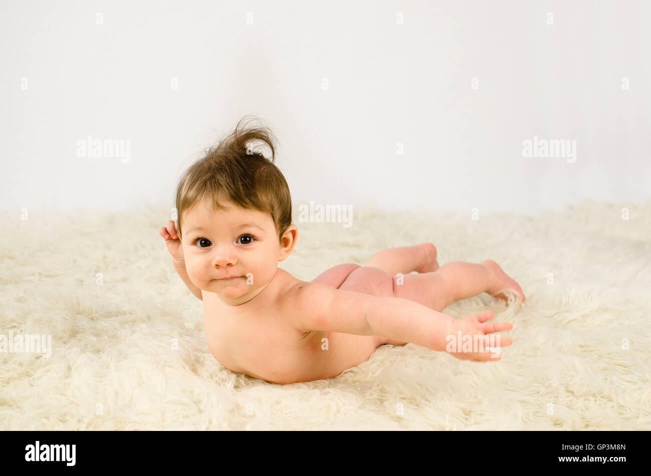 adorable baby girl lying naked on a flokati rug Stock Photo