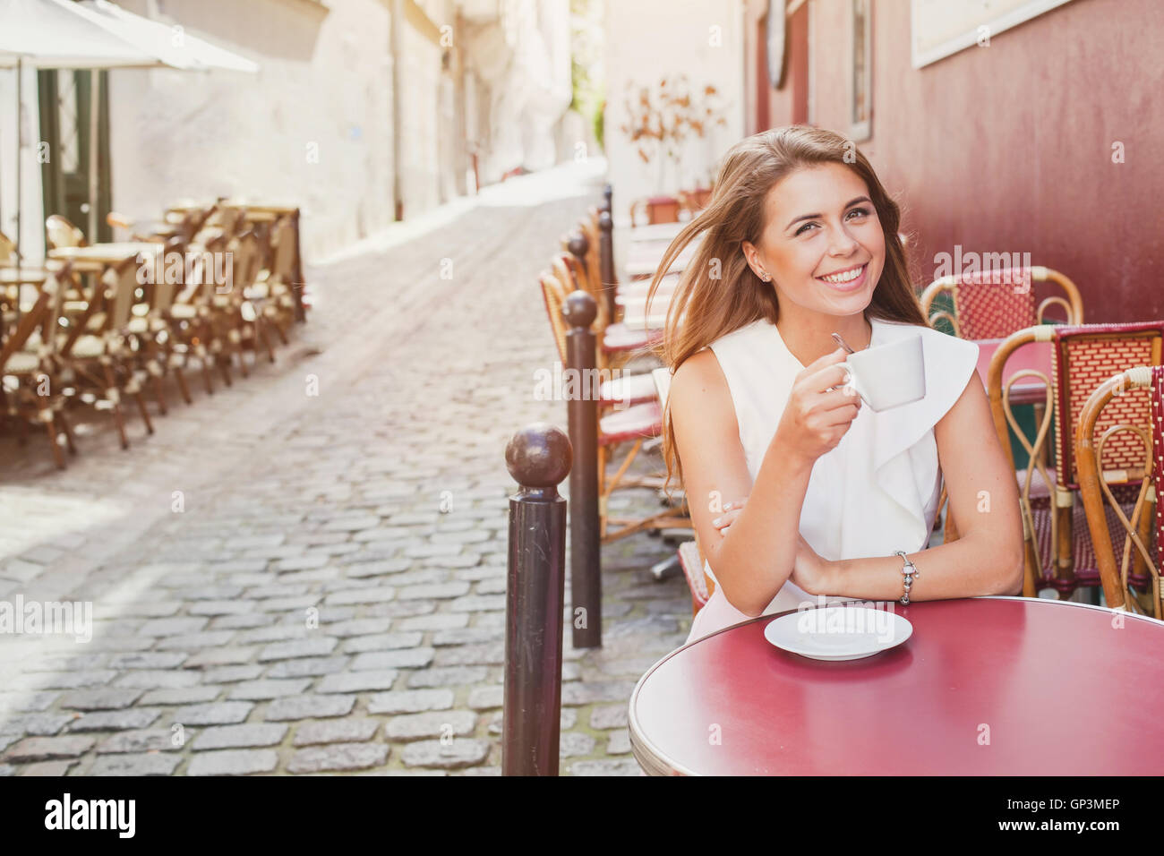 smiling woman drinking coffee in street cafe Stock Photo