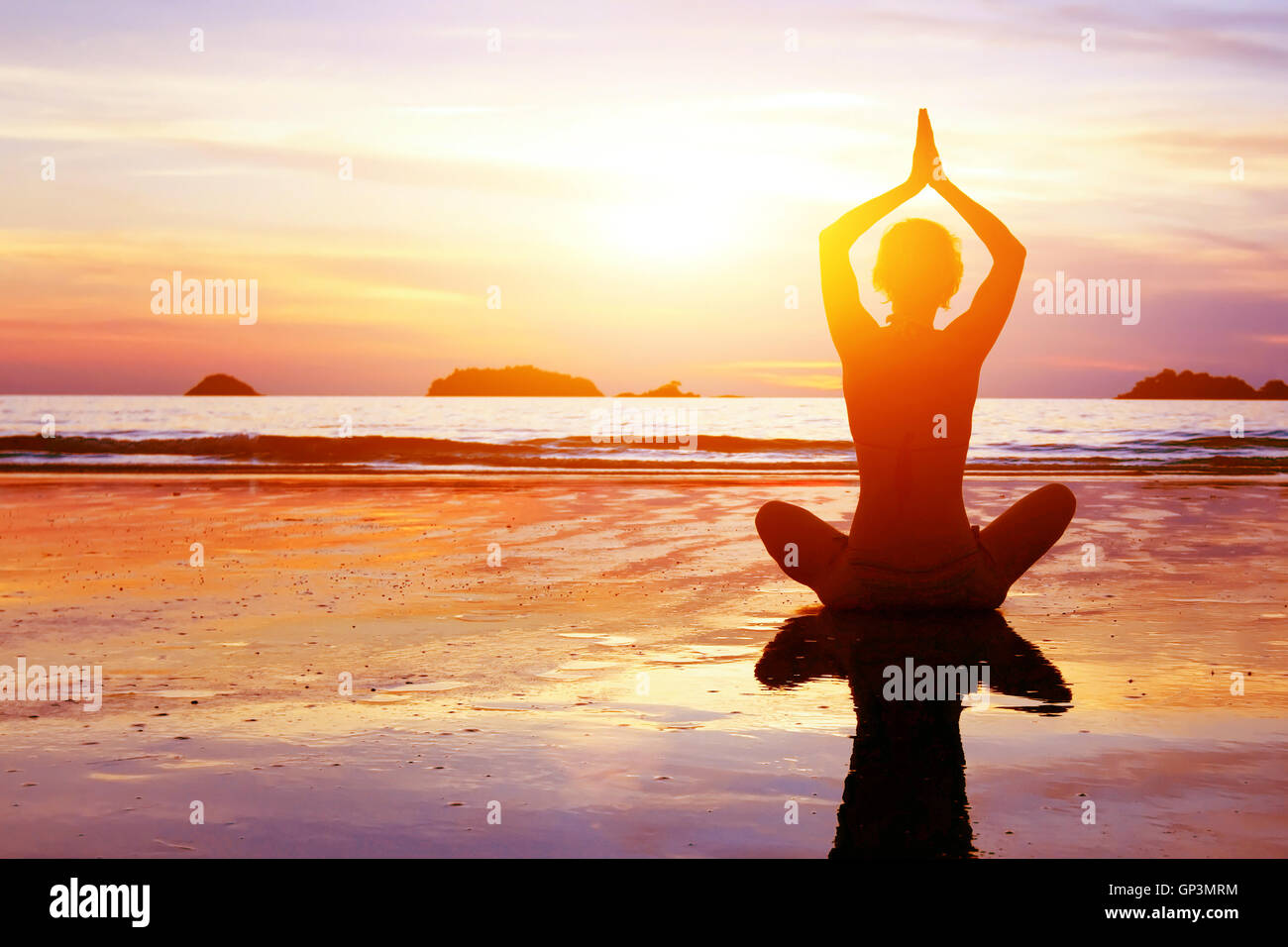 yoga and healthy lifestyle background, abstract silhouette of woman meditating on the beach Stock Photo