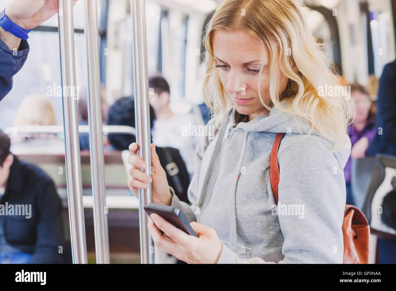 people in metro, commuters, woman passenger looking at the screen of her smartphone Stock Photo