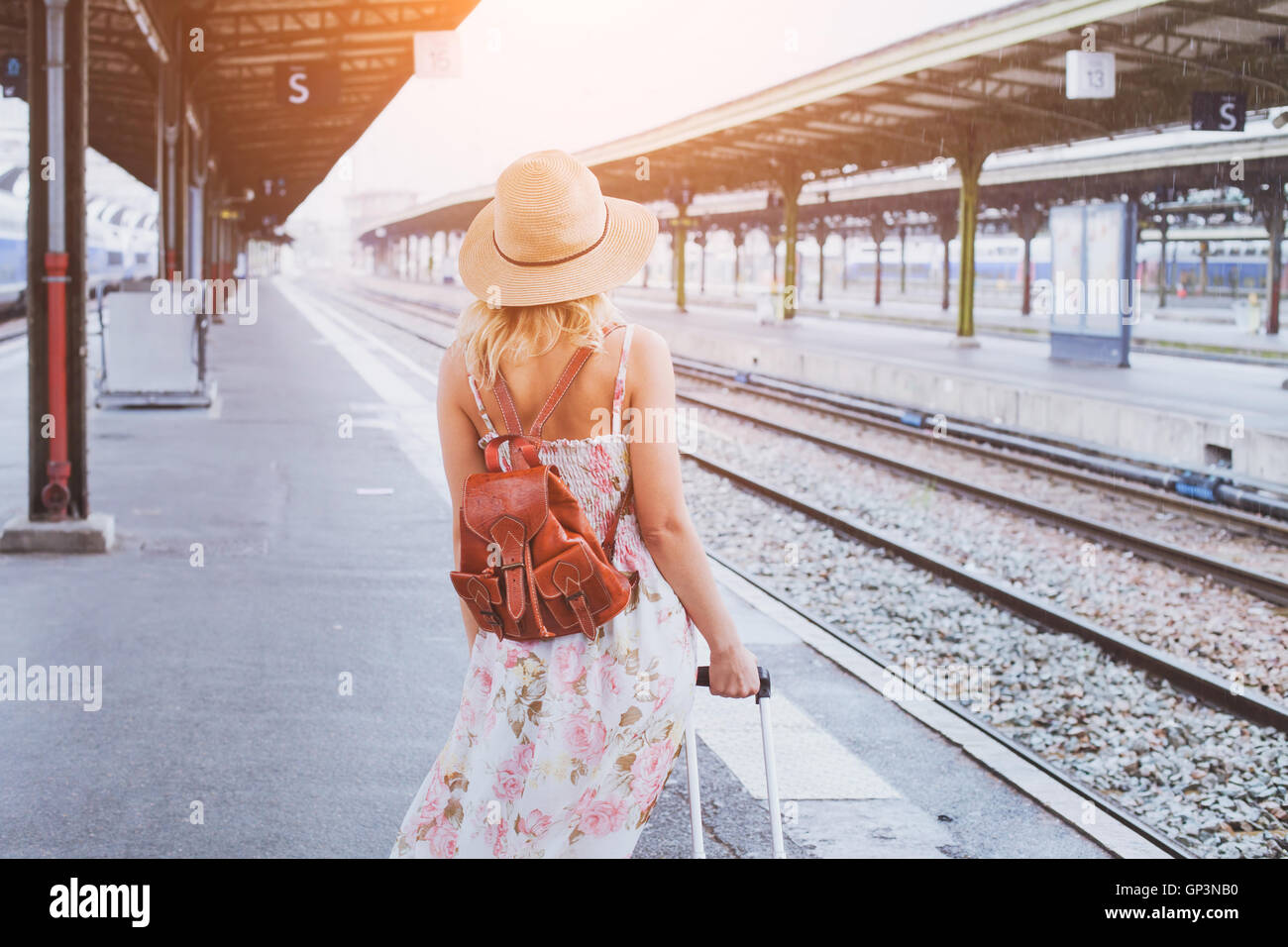summer travel, woman with suitcase waiting for  her train on platform of railway station Stock Photo