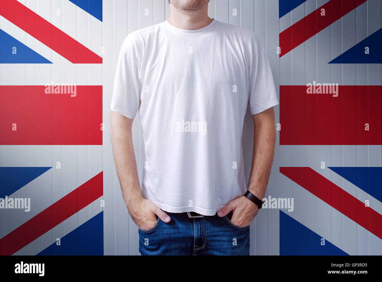 Man standing in front of United Kingdom flag wall, adult male person supporting Great Britain Stock Photo