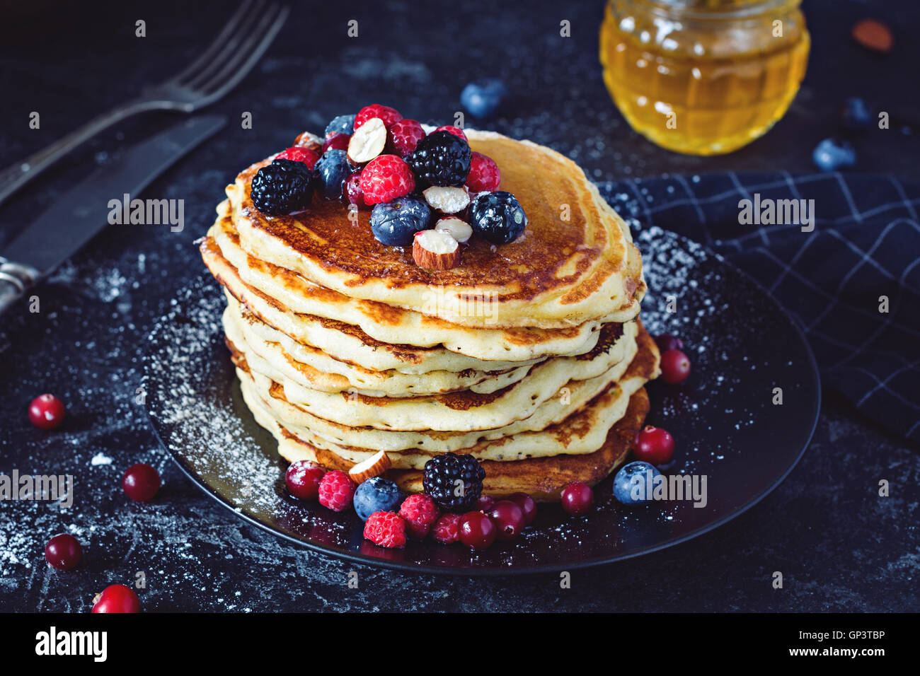 Delicious pancakes with fresh berries and honey on dark slate background, close up view Stock Photo