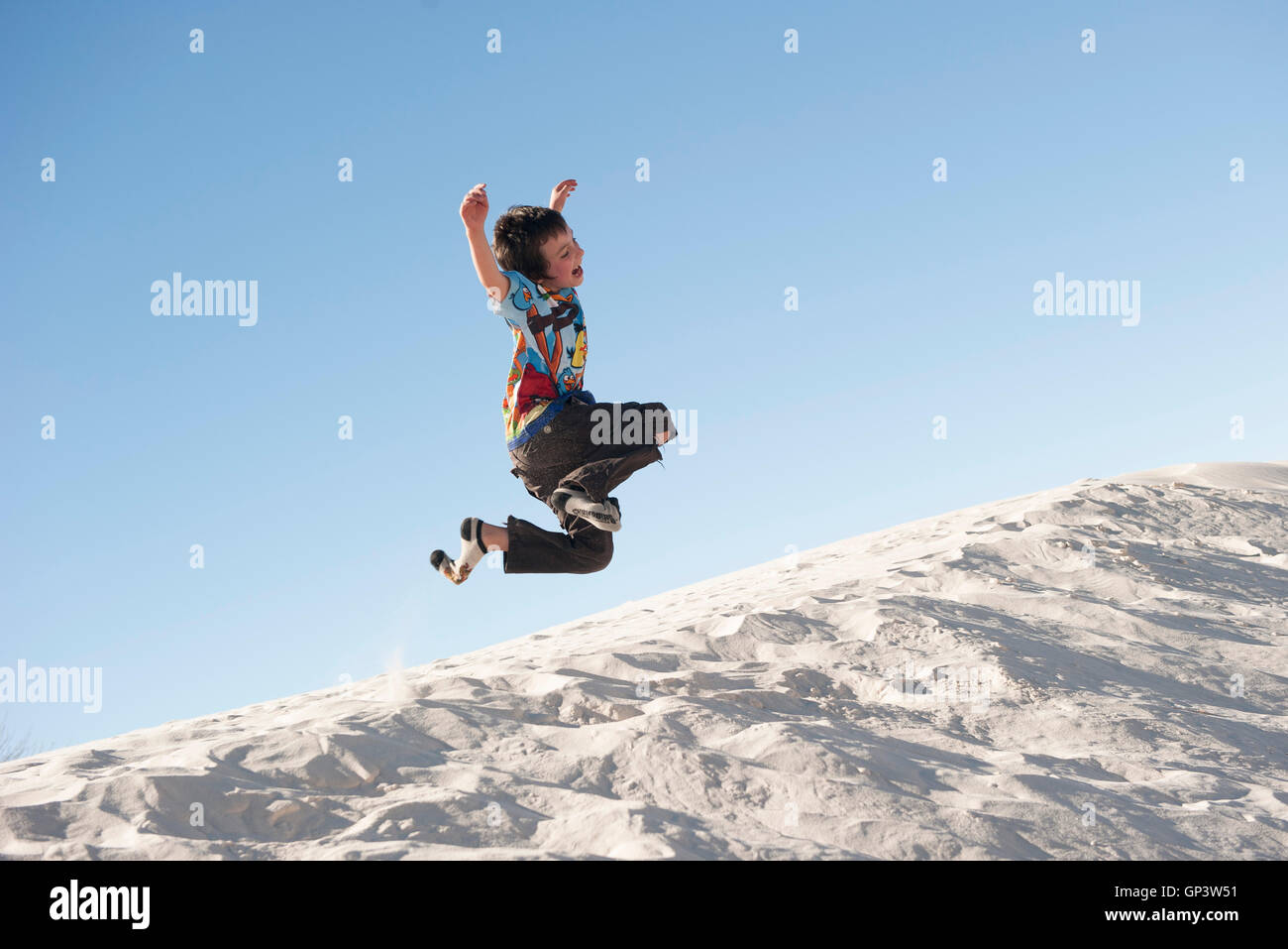 Boy jumping in midair over dune at White Sands National Monument, New Mexico, USA Stock Photo