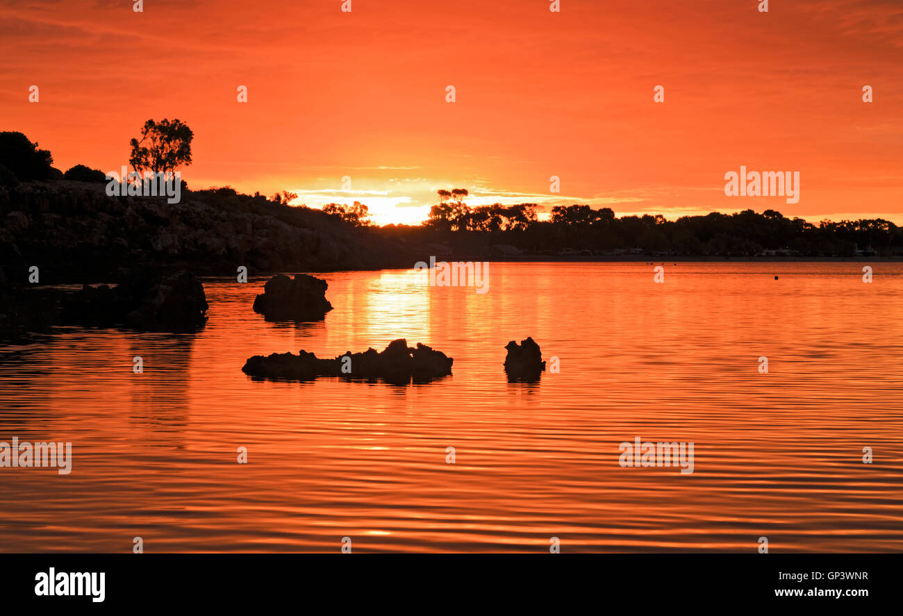 Bright orange-red sunset over horizon at Streaky Bay coast of Great Australian Bight. Still bay waters reflect burning sunsettin Stock Photo
