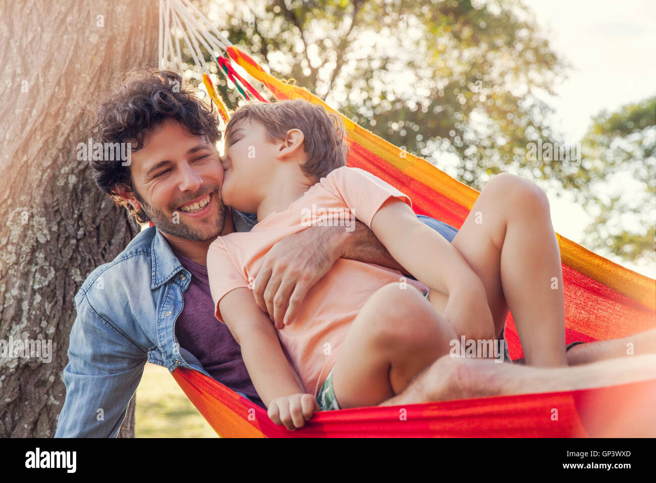 Father and son relaxing together in hammock Stock Photo
