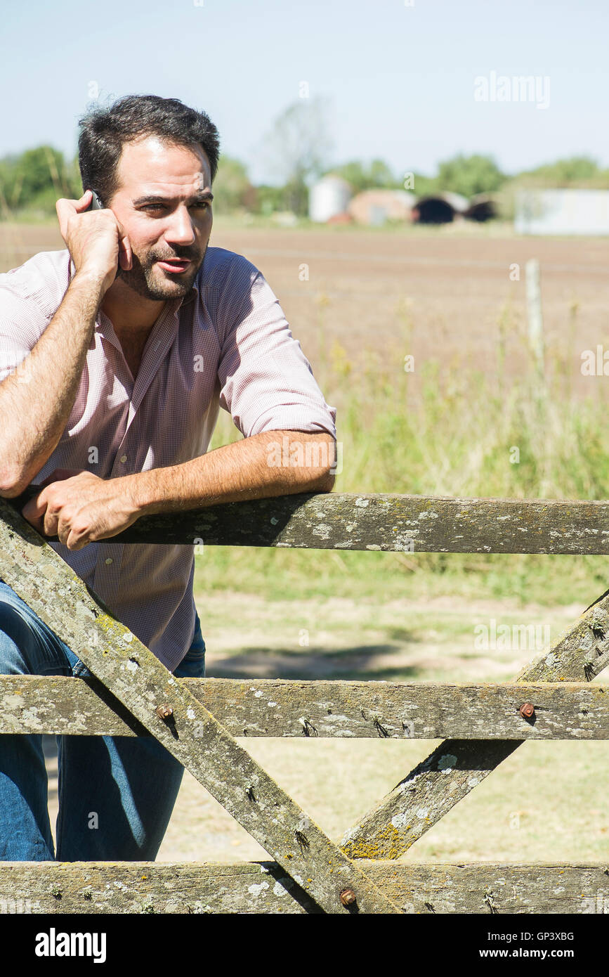 Farmer chatting on cell phone while surveying fields Stock Photo