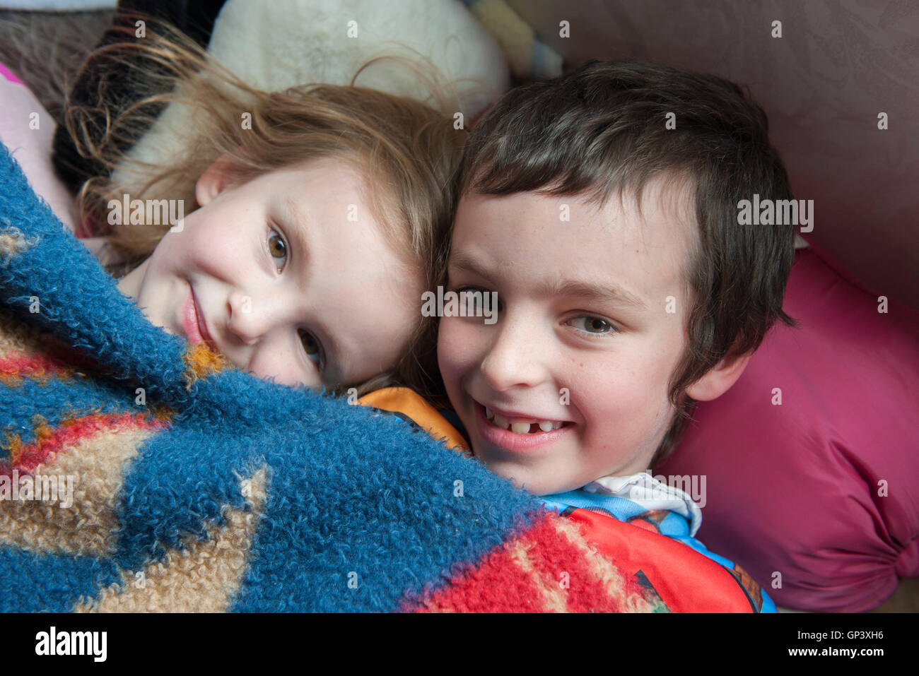 Young siblings lying under blanket together, portrait Stock Photo
