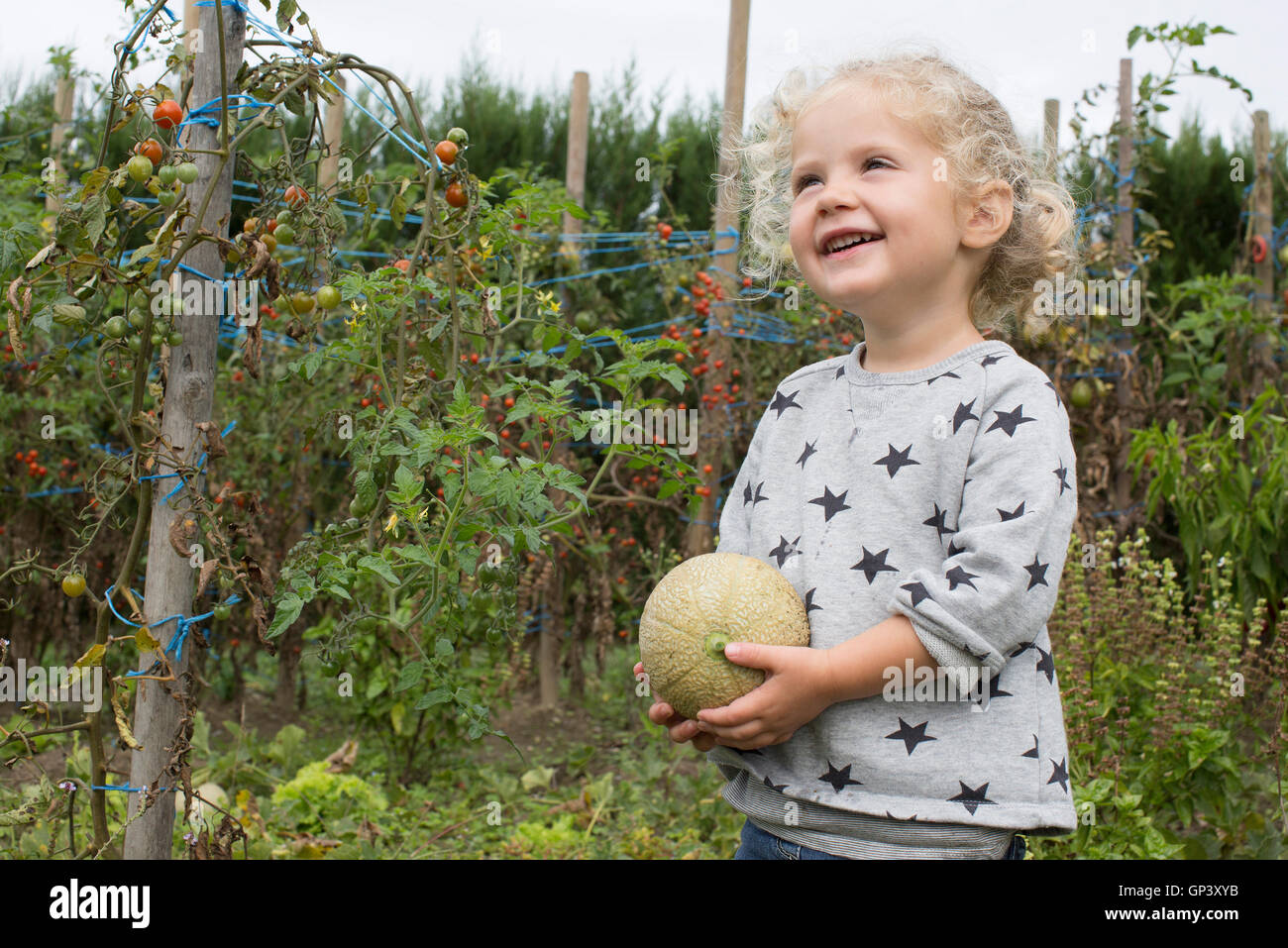 Little girl with cantaloupe in garden Stock Photo
