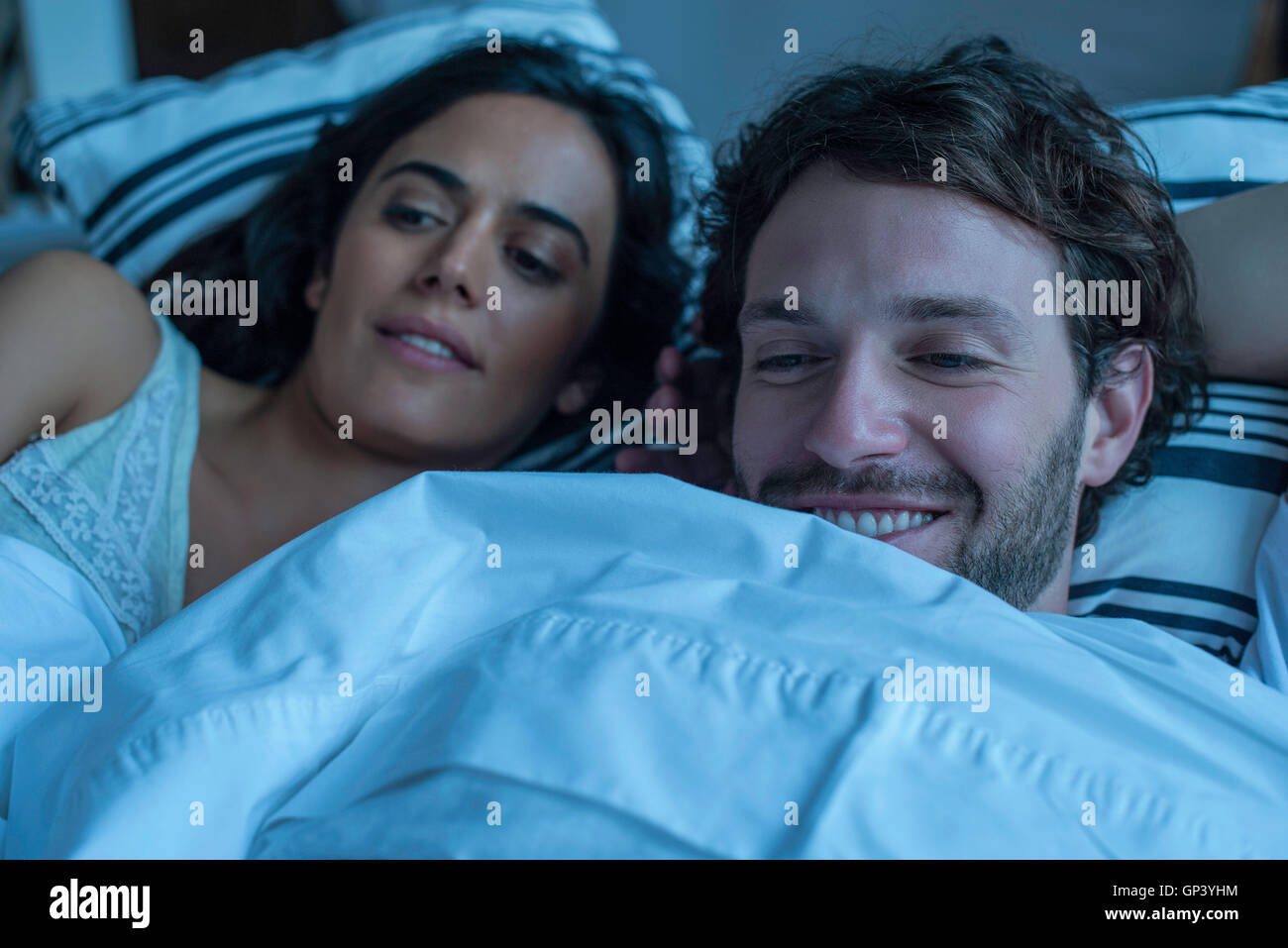 Couple watching tv together in bed Stock Photo Alamy