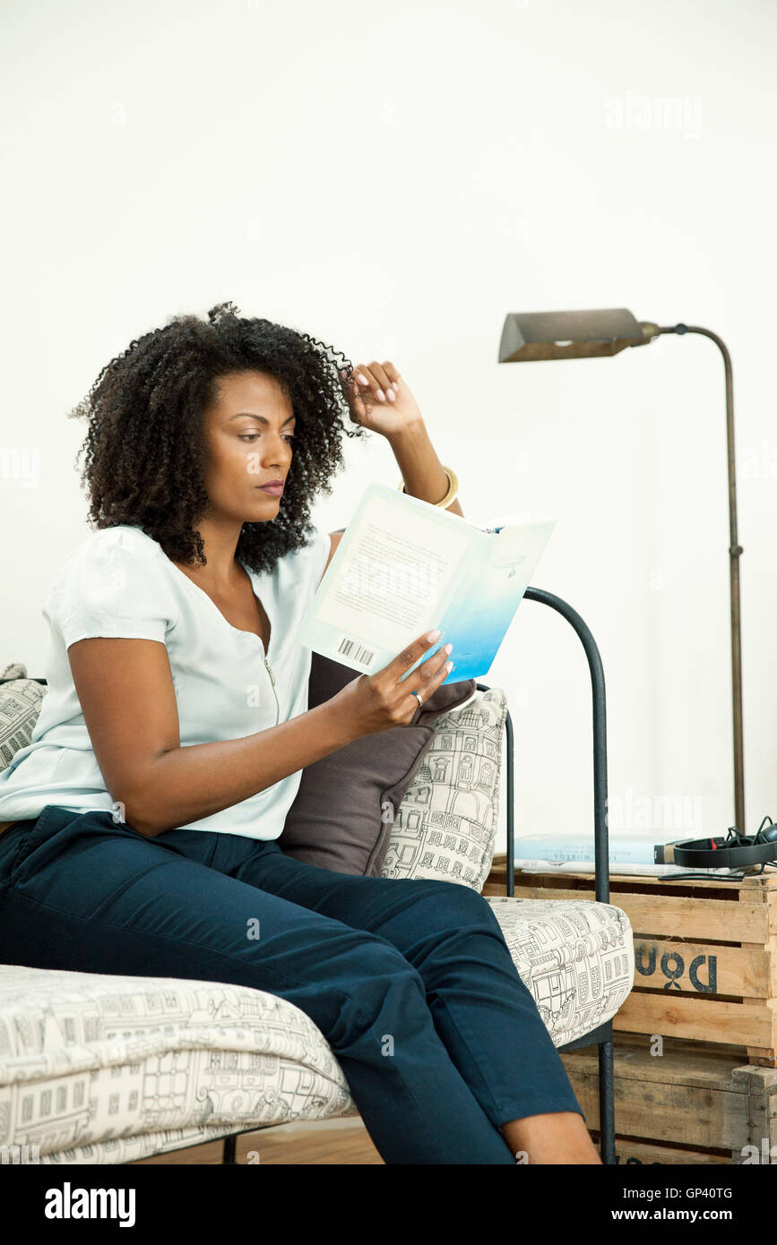 Woman relaxing at home with captivating novel Stock Photo