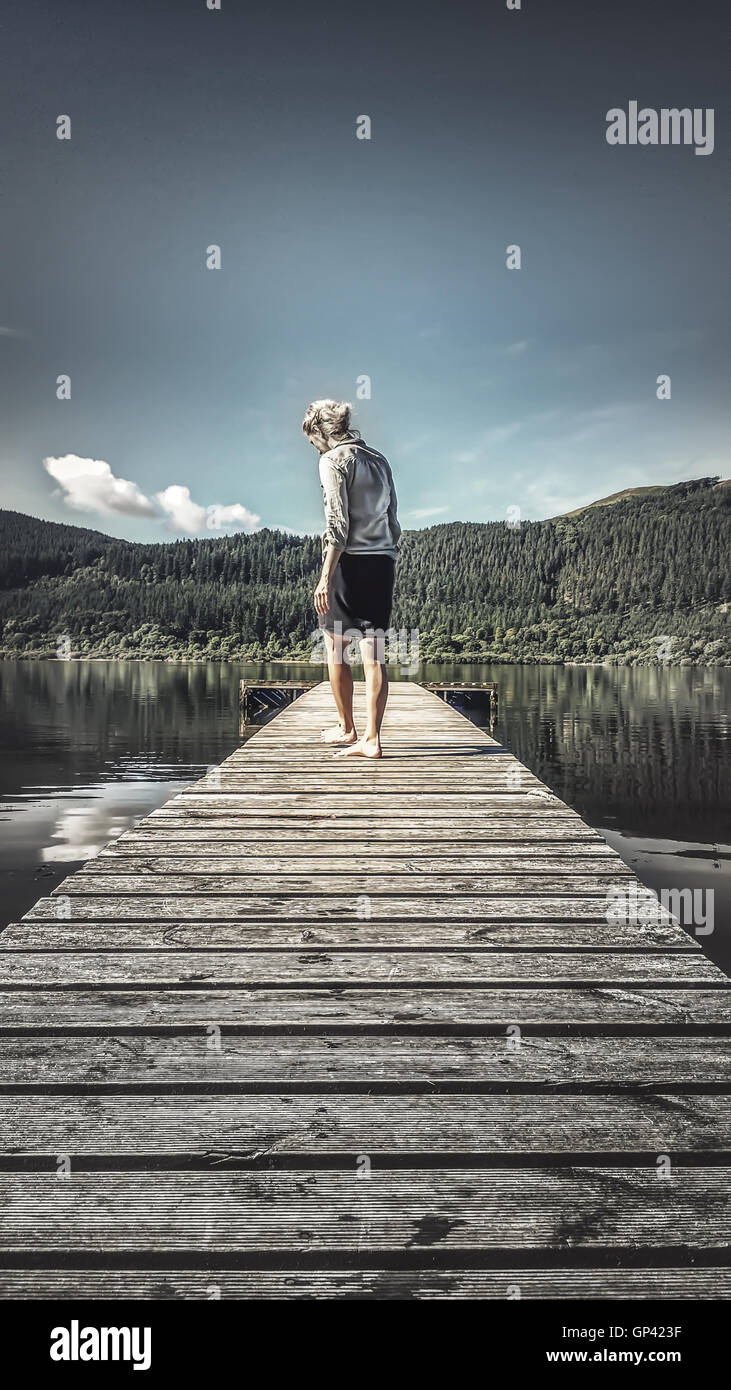 young woman walking on wooden bridge on lake Stock Photo
